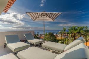 a patio with two chairs and an umbrella on a balcony at Villa Mangoni - Brand New Luxury Villa in Funchal