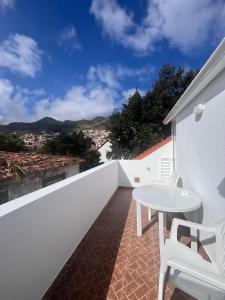 a balcony with a white table and white chairs at Machico Village Apartment - private terrace and car park in Machico