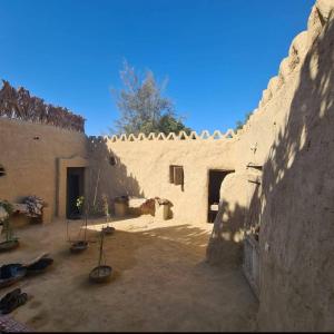a stone building with potted plants in a courtyard at Historical Mayor's House in Qasr Al Farafirah