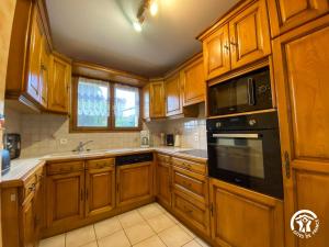 a kitchen with wooden cabinets and black appliances at Gîte du Cassan in Sénergues +5 photos