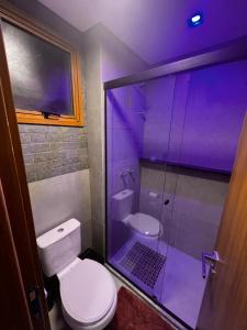 a bathroom with a toilet and a shower with purple lighting at Mucugê- Charm Village in Mucugê