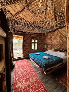 een groot bed in een kamer met een bakstenen muur bij La Colibe, cătun arhaic ecologic in Constanţa