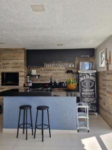a kitchen with a counter with stools and a refrigerator at Encantos do vale Teresópolis in Teresópolis