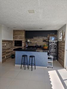 a kitchen with two bar stools and a counter at Encantos do vale Teresópolis in Teresópolis +39 photos