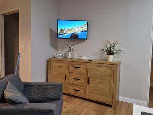 a living room with a tv on top of a wooden dresser at Kleiner Mövenschiß in Dorum-Neufeld