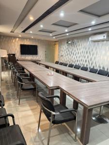 a conference room with tables and chairs and a flat screen tv at Hotel Golden in Lahore
