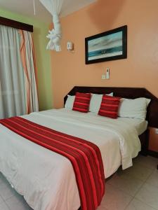 een slaapkamer met een groot wit bed met rode kussens bij Raya hotel Nyali Mombasa in Mombasa