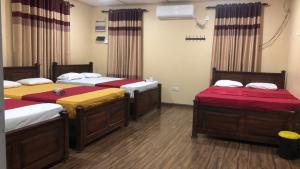 een kamer met drie bedden met rode en gele lakens bij St Anne's Hotel & Restaurant in Jaffna