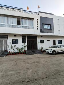 a white car parked in front of a building at NANDI Home Stay in Ujjain