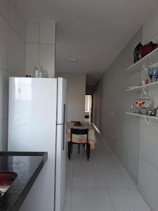 a white kitchen with a refrigerator and a table at Comfort right on the sand! in Paracuru +8 photos