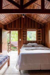 a large bed in a wooden room with a window at Pousada Ypê das Montanhas in Monte Alegre do Sul +21 photos