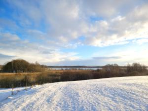 een met sneeuw bedekte weg in een veld met een hemel bij Wyskok 1 - dom z widokiem in Srokowo