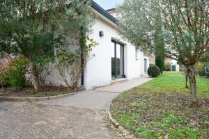 a white house with a sidewalk and trees in front of it at Maison Épure - maison mitoyenne avec jardin in Colomiers