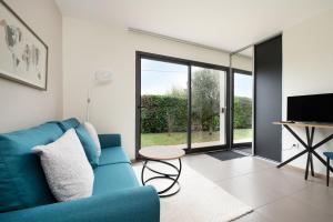 a living room with a blue couch and a tv at Maison Épure - maison mitoyenne avec jardin in Colomiers