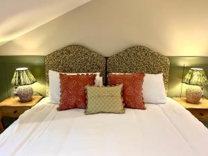 een bed met rode en witte kussens en 2 lampen bij The Fox Inn in Ansty