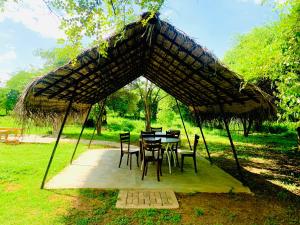 a table and chairs under a straw umbrella at Thihawa Yala in Tissamaharama