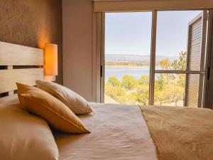 a bedroom with a large bed with a large window at PUEBLO CHICO - casas de lago in Villa Ciudad de América
