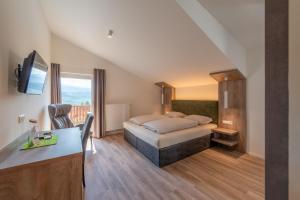 a small hotel room with a bed and a desk at Beim Sarner in Caldaro
