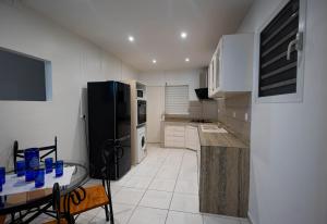 a kitchen with a glass table and a black refrigerator at Kanelle in Baie-Mahault