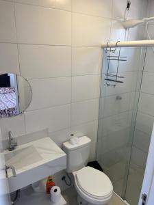 a bathroom with a toilet and a glass shower at Ap Alto São Bento in Itapema