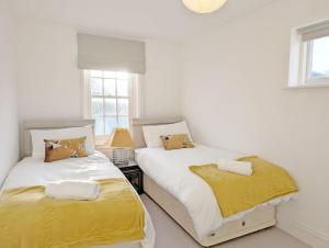 two beds in a room with white walls and windows at 1a Tower Street - Emsworth in Emsworth