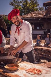 Een man met een rode hoed maakt pizza. bij La Colibe, cătun arhaic ecologic in Constanţa
