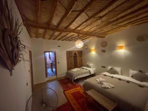 a bedroom with two beds and a wooden ceiling at Hotel Soleil Blue in Boumalne Dades