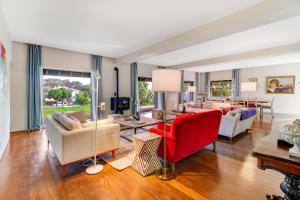 a living room with couches and a red chair at Chalet da Azenhas in Colares