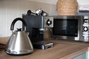 a kitchen counter with a microwave and a tea kettle at Hop Pickers Cottage in Little Marcle