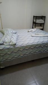 an unmade bed with a chair in a bedroom at Apê Ponta da Praia Santos in Santos
