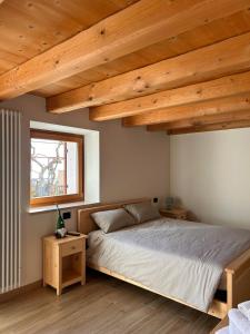 a bedroom with a bed and a window and wooden ceilings at Agriturismo El Bocolar in Marano di Valpolicella