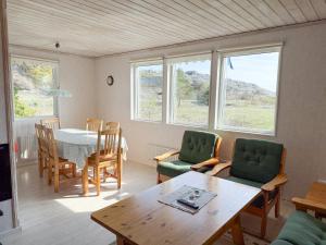a living room with a table and chairs and windows at Nobel Cabins - Furillen in Lärbro