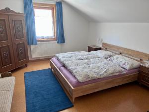 a bedroom with a bed with a blue rug and a window at Ferienwohnung Feicht`n Schuster in Gosau