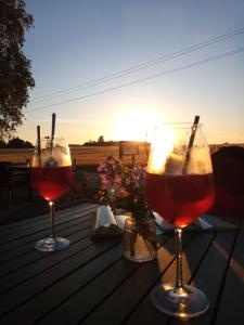two glasses of wine sitting on a table with the sunset at Fischstübchen Neeberg Fewo 2 - Achterwasser in Krummin