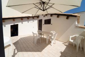 a patio with a table and chairs and an umbrella at Le Amiche in Marina di Ragusa