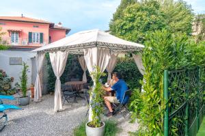 un hombre sentado bajo un paraguas en un jardín en B&B La Mimosa, en Lucca