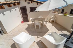 a patio with a table and chairs and an umbrella at Le Amiche in Marina di Ragusa