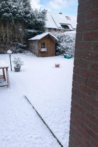 a yard covered in snow with a wooden shed at Studio confortable situé à Woluwe Saint Lambert in Brussels +3 photos