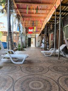 a patio with white lounge chairs and palm trees at Arrullos del Mar in Zorritos