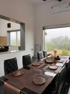 a dining room table with chairs and a large window at Casa Oceanus - Sea Facing Forest View Room - Ganpatipule in Nevra
