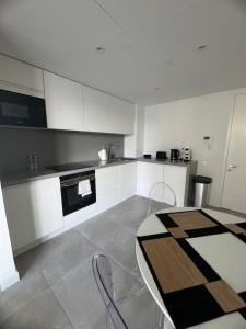 a kitchen with white cabinets and a table with chairs at VV - Skyline Studio Pool & Gym in City Centre in Gibraltar