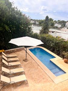 a white umbrella and chairs next to a swimming pool at Villa Imperial in Cala d´Or