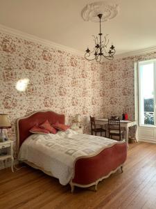 een slaapkamer met een bed, een tafel en een kroonluchter bij Le Manoir des Rochers in Bouère