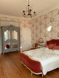 een slaapkamer met een groot bed en bloemenbehang bij Le Manoir des Rochers in Bouère