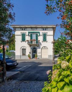 a white building with green shutters on a street at B&B La Mimosa in Lucca