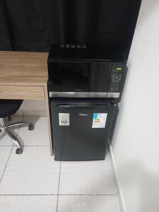 a black microwave oven sitting next to a desk at Suíte casal Bela Vista 207 in São Paulo