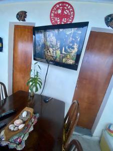 a dining room table with a television on a wall at Hospedagem Mandala in Ubatuba