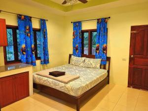 a small bedroom with a bed with blue curtains at Jasmine's Bungalow in Ban Saiyuan (1)