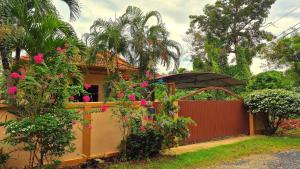 a house with pink flowers and a fence at Jasmine's Bungalow in Ban Saiyuan (1)