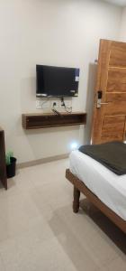 a bedroom with a bed and a tv on a wall at SRI KRISHNA LODGE in Hosūr